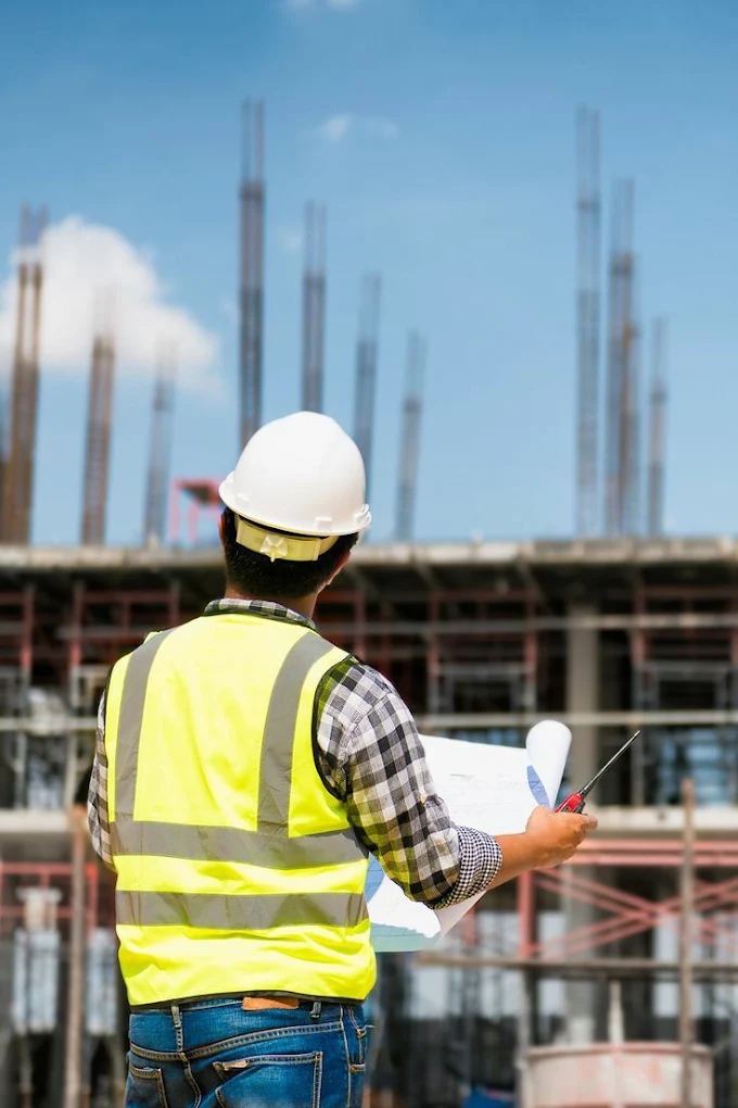 Inginer de șantier verificând planurile unei construcții aflate în lucru